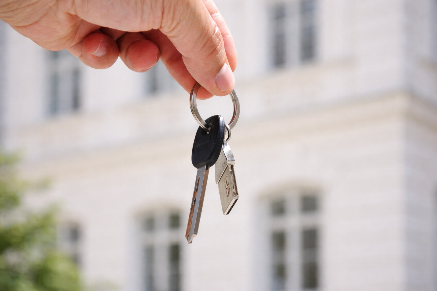 Hand holding keys in front of a building